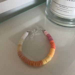 Färgglatt armband med pärlor - Säljer ett superfint armband med färgglada pärlor i nyanser av vitt, gult, orange och rosa. Armbandet har en justerbar kedja och ett smidigt lås. Perfekt för att liva upp vilken outfit som helst!