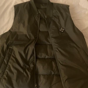 J. Lindeberg väst  - Helt oanvänd J.Lindeberg väst, Fick i present men den har bara legat i klädkammaren. Köpt i butik. Den är Storlek M men passar även S. Du kan vända den ut och in som du ser på bilden. Ordinarie pris 2300.