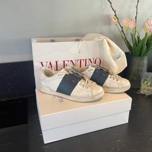 Säljer ett par snygga Valentino sneakers i vitt och blått. De har en cool design med breda blå ränder och är tillverkade i skinn. Skorna är i välanvänt skick men fortfarande riktigt stiliga. Pris ej hugget i sten!