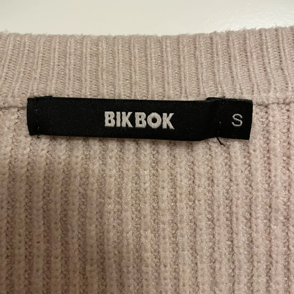 Säljer en superfin beige stickad kofta från BikBok. Den har en dragkedja framtill med en cool ringdetalj och är ribbad för en snygg look. Perfekt för höst och vinter när du vill hålla dig varm och stilren. Koftan är i storlek S och passar perfekt till både jeans och kjol. 🧥✨. Tröjor & Koftor.