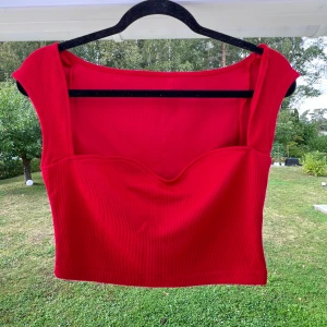 Röd crop top - En röd crop top med hjärtskärning. Säljer den pga att den är en aning stor till mig ❤️  (ALDRIG ANVÄND)  Längd: 33 cm Byst: 80 cm
