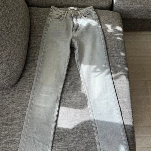Grå jeans med slit  - Grå jeans från zara i strö 32 (xs). modell split slim. Helt oanvänd. Passform: tight över lår och lösare mot vad, med öppen slit vid ankeln.