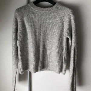 Grå stickad tröja från Pieces - Säljer en supermysig grå stickad tröja från Pieces. Perfekt för kyliga dagar med sin mjuka och bekväma passform. Tröjan har långa ärmar och en klassisk rund halsringning. Passar både till vardags och lite finare tillfällen. Den slutar vid midjan och är knappt använd. 💫