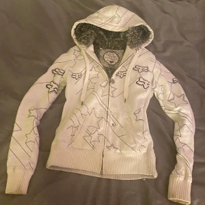 Vit hoodie med pälsfoder från Fox - Säljer en vit hoodie från Fox med svart mönster. Bra skick förutom en fläck(bild 4)och lite smutsig på ärmarna. Päls på både insidan av luvan och tröjan, perfekt nu till vintern! Storlek S/M. Pris kan diskuteras, skriv för fler bilder/frågor💕