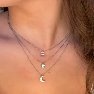 Silverhalsband med bokstaven E - Snyggt silverhalsband med en hängande bokstav E, dekorerad med små stenar. Kedjan är tunn och elegant, vilket gör den lätt att bära varje dag. Halsbandet är 42cm långt men går att ljustera kortare.