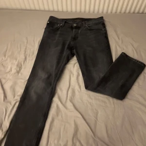 Svarta jeans från Nudie Jeans - Säljer ett par svarta jeans från Nudie Jeans (grim trim dark cove) i storlek 32/30. Den är i mycket bra skick. Skitsnygga och passar bra till många tillfällen. Enkelt att styla med vad som helst. Nypris 1600kr