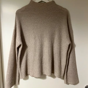 Beige stickad tröja från Vila - Mysig beige stickad tröja från Vila med lång ärm och hög krage. 