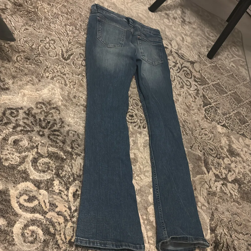 Säljer ett par blå bootcut jeans från H&M. De har en låg midja och justerbar midja för perfekt passform. Perfekta för en avslappnad stil.. Farkut & Housut.