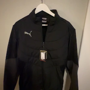 Svart jacka från Puma helt ny - Säljer en svart jacka från Puma i mycket bra skick. Den har en dragkedja framtill och är långärmad. Perfekt för höst och vår med sin stilrena design och bekväma passform.