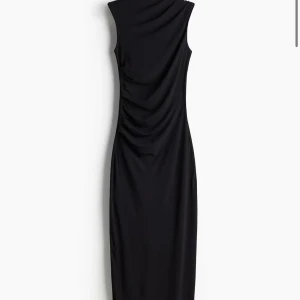 Svart ärmlös klänning - Snygg svart långklänning i ett elegant och stilrent snitt. Den är ärmlös och har en draperad detalj som ger en smickrande passform. Perfekt för festliga tillfällen eller en kväll ute. 