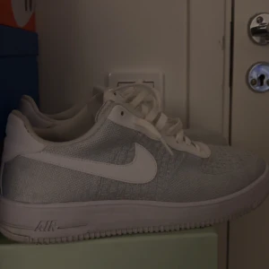 Nike Air Force flyknit i vitt - Snygga vita Nike Air Force sneakers med klassisk design och snörning. Perfekta för en stilren look.