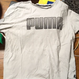 Vit t-shirt från Puma - Säljer en vit t-shirt från Puma med stort tryck på framsidan. T-shirten är kortärmad och tillverkad i bomull, perfekt för en avslappnad stil.