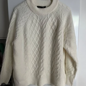 Vit stickad tröja från Lager 157 - Mysig vit stickad tröja från Lager 157 i storlek L. Perfekt för kyliga dagar med sitt klassiska flätmönster. Tröjan har långa ärmar och en bekväm passform. Lite slitage syns på framsidan, men den är fortfarande i bra skick. Perfekt för höst och vinter!