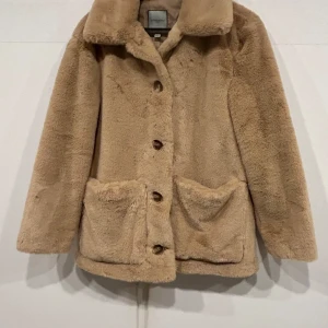Beige teddyjacka från Urbancode - Supermysig beige teddyjacka från Urbancode i storlek M. Perfekt för kalla höst- och vinterdagar. Jackan har långa ärmar och knappar framtill, samt två stora fickor. Den är i mycket bra skick och redo för nya äventyr! 🧥✨Använd några gånger. Ord pris 2100kr säljer till bara 600kr.