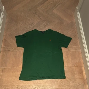Grön t-shirt från Ralph Lauren - Säljer en snygg grön t-shirt från Ralph Lauren i storlek XL. Den har en klassisk passform och är kortärmad, perfekt för både vardag och avslappnade tillfällen. Den är i bra skick men ändå använd. Säljer för att den är för liten för mig:) 