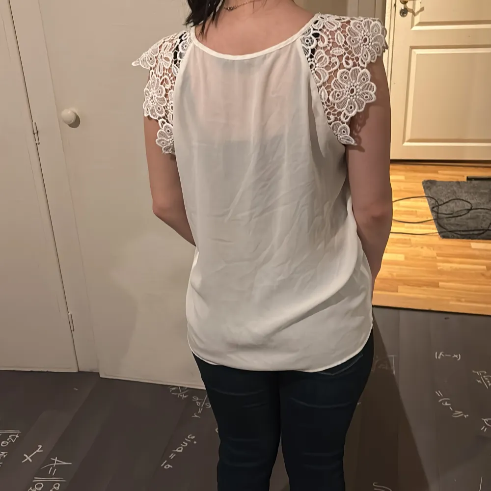 Säljer en stilren vit blus från Zara Basic med vackra spetsdetaljer på axlarna. Blusen är ärmlös och har en rund halsringning. Perfekt för en elegant look.. Yläosat.