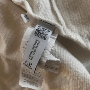 Vit huvtröja från C.P. Company - Säljer en vit huvtröja från C.P. Company i storlek M. Tröjan har en dragkedja framtill och är långärmad. Den är i bra skick men har en liten fläck på framsidan. Perfekt för höst och vår!