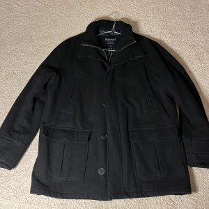 Svart rock från Redwood - Snygg svart rock från Redwood med knappar framtill och praktiska fickor. Perfekt för kyligare dagar med sin stilrena design och bekväma passform.