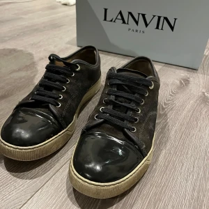 Svarta sneakers från Lanvin - Snygga svarta sneakers från Lanvin med glansiga detaljer på tån och snörning. få med box och dust bag. hör av er vid minsta fundering