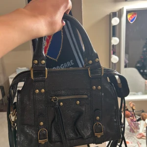 Svart handväska med detaljer - Jättesnygg väska med guldiga detaljer! Köpt på en marknad i Grekland för ca 1500kr, säljer då den aldrig kommer till användning!