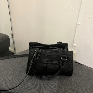 Svart axelväska med dragkedja - Säljer denna väska från Gina tricot. Den är i nyskick. Följer med axelrem men går även att ta av. Kontakta vid funderingar😊