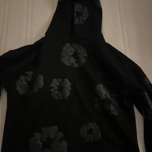Svart hoodie från Denim Tears - Hej säljer denna denim tears hoodie då den va för stor för mig, den är inte använd en ända gång förutom när jag testade den. På sista bilden ser du hur den sitter! Om du vill ha fler bilder eller undrar över något så är det bara att skriva!😄