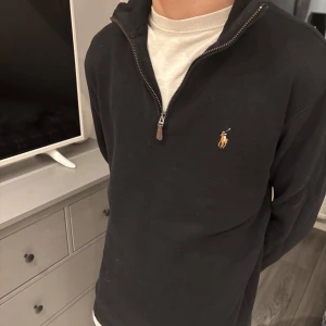 Halfzip  Ralph Lauren - Säljer en stilren svart tröja från Ralph Lauren med dragkedja och klassisk logga på bröstet. Perfekt för en avslappnad men snygg look. Sitter som s