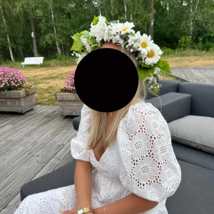 Vit klänning med puffärmar - Charmig vit klänning med vackert broderat mönster och puffiga trekvartsärmar. Perfekt för sommarens festligheter med en romantisk touch. Klänningen har en v-ringad hals och en elegant passform.