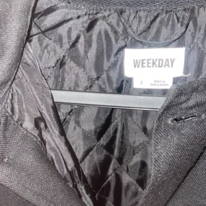 Svart jacka från Weekday - Säljer en stilren svart jacka från Weekday i storlek S. Jackan har en klassisk design med knappar framtill och två bröstfickor. Perfekt för en minimalistisk look.