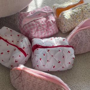 Färgglada quiltade necessärer - Säljer ett set med quiltade necessärer i olika mönster och färger. De har dragkedja och kommer i mönster som rutigt rosa, blommigt gult och vitt med körsbär. Perfekta för att organisera dina småsaker. Endast körsbär kvar!! 189kr/st 