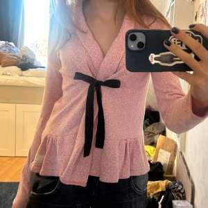 Rosa omlottkofta från Odd Molly - Säljer en söt rosa omlottkofta från Odd Molly med ett diskret mönster rosa/vitt och mörkblått knytband framtill. 