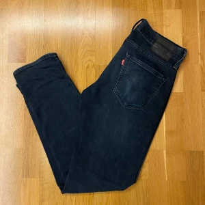 Levis 511 - Snygga mörkblå jeans med klassisk femficksdesign och knappgylf. Perfekta för en stilren look. De har en diskret logga på bakfickan och är tillverkade i ett slitstarkt material.             Skick 9/10. Str 32/32. Pris är diskuterbart! 