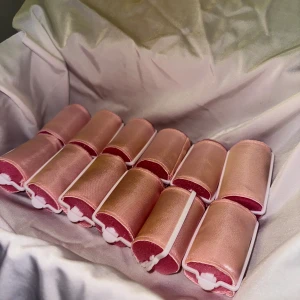 Rosa silkes-papiljotter  - Säljer ett set med rosa hårspolar i satin. Perfekta för att skapa mjuka lockar utan värme. Setet innehåller flera spolar och ett långt band för att hålla dem på plats. Perfekt för en skonsam styling.