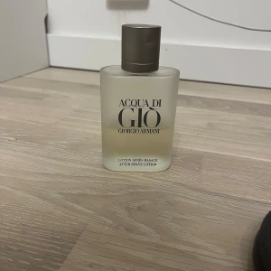 Acqua di Giò After Shave Lotion från Giorgio Armani - Säljer en flaska Acqua di Giò After Shave Lotion från Giorgio Armani. Den är runt 40% full. Flaskan är frostad och har en stilren design med en grå kork. Perfekt för att fräscha upp efter rakning med en klassisk doft.