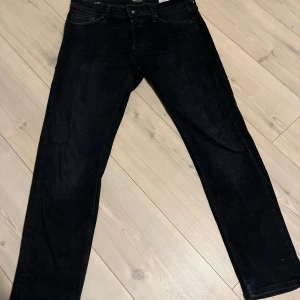 Svarta jack and jones jeans - Snygga svarta jeans med tapered fit. De har en klassisk design med fem fickor och knappgylf. Perfekta för en stilren look. De är i nyskick, skriv vid funderingar