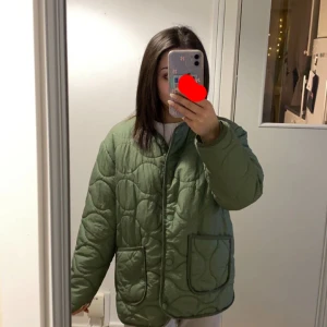 Grön quiltad jacka från H&M - Säljer en snygg grön quiltad jacka. Jackan har en oversized passform med långa ärmar och knappar framtill. Perfekt för höst och vår med sin stilrena design och bekväma känsla. Säljer då den inte kommer till användning längre!