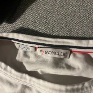 Vit t-shirt från Moncler - Säljer en stilren vit t-shirt storlek S men väldigt slim fit från Moncler med korta ärmar och en broderad logga på ärmen.