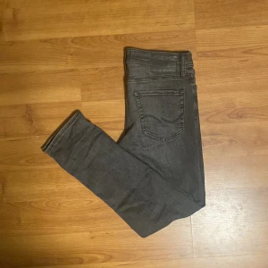 Grå jeans från Jack & Jones - Snygga grå jeans från Jack & Jones i modellen Slim/Glenn. De har en slim passform och är tillverkade i ett bekvämt material. Skick 6/10 lite lösa trådar, små slitningar men inget som går rakt igenom och små smutsfläckar men inget som inte går bort i tvätten! 👌storlek 30/30 💯vid fler frågor kom privat! 👍✅