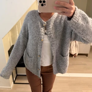 Ljusblå stickad kofta med knappar - Mysig blå stickad kofta med guldknappar och två fickor framtill. Perfekt för kyliga dagar och ger en avslappnad look. Koftan har långa ärmar och en mjuk textur. 💙😃