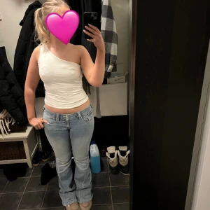 Vit oneshoulder topp från Gina Tricot - Säljer en stilren vit oneshoulder topp från Gina Tricot. Perfekt för en trendig look med sin asymmetriska design. Toppen är i ett mjukt och bekvämt material som passar bra till både jeans och kjol. Ett måste i garderoben för den modeintresserade!