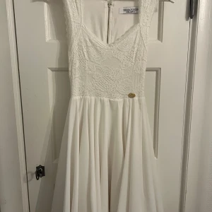 Vit spetsklänning från Chiara Forthi - Elegant vit klänning från Chiara Forthi med v-ringad spetsöverdel och dragkedja i ryggen. Perfekt för speciella tillfällen som exemelvis studenten! Endast använd vid ett tillfälle