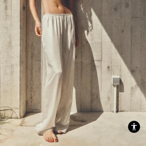 Vita satinbyxor - Eleganta vita byxor i satin med en loose passform. Perfekta för en stilren look med en bekväm känsla. Byxorna har en enkel design med resår i midjan för extra komfort. Helt nya, prislapp kvar! 