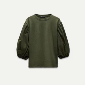 Khaki topp från Zara - Snygg topp från Zara med puffiga trekvartsärmar. Perfekt för en stilren look med en touch av elegans. Tillverkad i ett mjukt material som ger en bekväm passform. Helt ny, endast testad, prislapp kvar. Slutsåld på hemsidan.