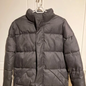 Grå pufferjacka (S) - Säljer en stilren grå pufferjacka från Jack&Jones med hög krage och dragkedja. Aldrig använd pga felköp. 