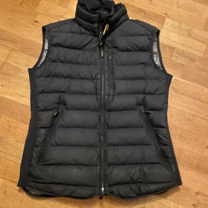 Svart dunväst från Parajumpers - Säljer en svart dunväst från Parajumpers i storlek XL. Västen är superlätt och har en dragkedja framtill samt två fickor med dragkedja. Perfekt för kyligare dagar. Det står XL i västen men den passar mig som är 178 cm som du ser här den ett lite hål där fram men går att sy. Scan fungerar utmärkt och västen är köpt här på plick och han sa att den var äkta köpte den för 1600 priset går att diskutera vid snabb affär 