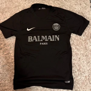 Psg x Bailman t-shirt - Säljer en snygg t-shirt från Psg x Bailman. Tröjan är knappast använd det enda synliga är loggan i nacken där man ser storleken som har försvunnit annars inga fel. Hör av dig vid frågor!
