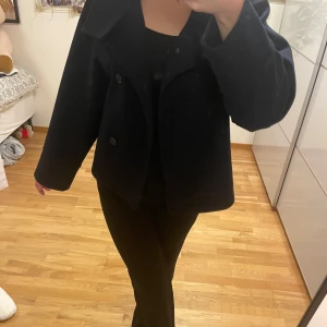 Marinblå kappa från Ginatricot - Säljer denna marinblåa kappa, då den inte kommit till användning många gånger. En kortare och boxig modell i storlek XS. Den stängs med knappar i fram.