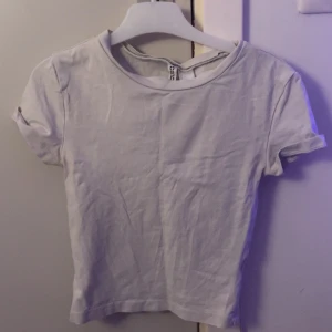 Vit kortärmad topp från H&M Divided - Den är använd, har en fläck men är fin endå. Fläcken synns inte mycket. Dock är den jätte tajt. I storlek xs. Den har tvättas flera gången så den vita färgen är inte som i ny skick. Behövs det bild på så kan jag gärna skicka ☺️ Frakten står jag ej för! ❤️ 