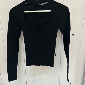 Svart långärmad topp från Zara - Snygg svart långärmad topp från Zara med fyrkantig halsringning. Perfekt för en stilren look. Tillverkad i ett stretchigt material som ger en tight passform.
