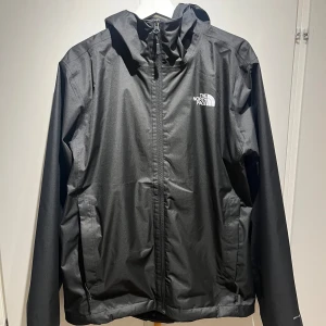 Svart regnjacka från The North Face - Säljer en stilren svart regnjacka från The North Face. Jackan har en praktisk huva och dragkedja framtill. Perfekt för regniga dagar och håller dig torr och bekväm. The North Face-logga på bröstet och ryggen. Skriv vid intresse för fler bilder eller om du har någon fråga! 